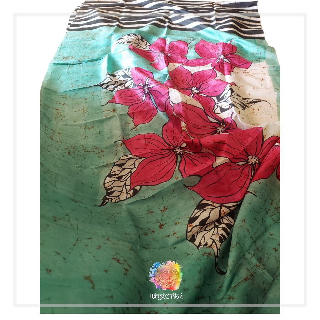 Hand-painted batik silk saree with pink floral design on a green and blue background.