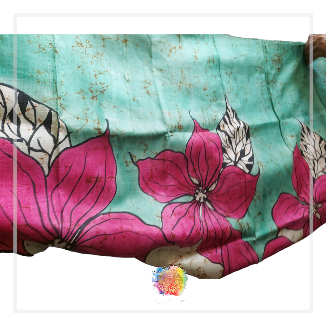 Hand-painted batik silk saree with pink floral design on a teal background.