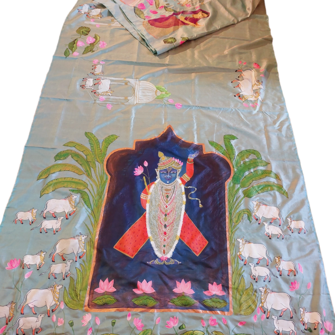 Hand-painted Pichwai Tussar silk saree featuring a Krishna and cow design on a blue silk fabric.