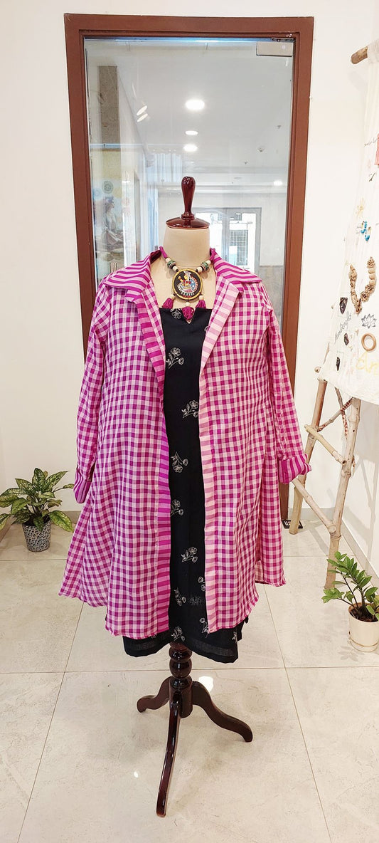 S long magenta and white checkered Gamcha shrug over a black floral embroidered midi dress with a statement tribal necklace.